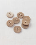 Huit boutons ronds beige taupe de 15 mm à 2 trous, gravés de rayons en forme de soleil, dont un vu de dos lisse et nacré