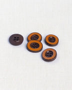 Boutons ovales marron et orange de 18 mm à 4 trous posés en biais sur une toile écrue