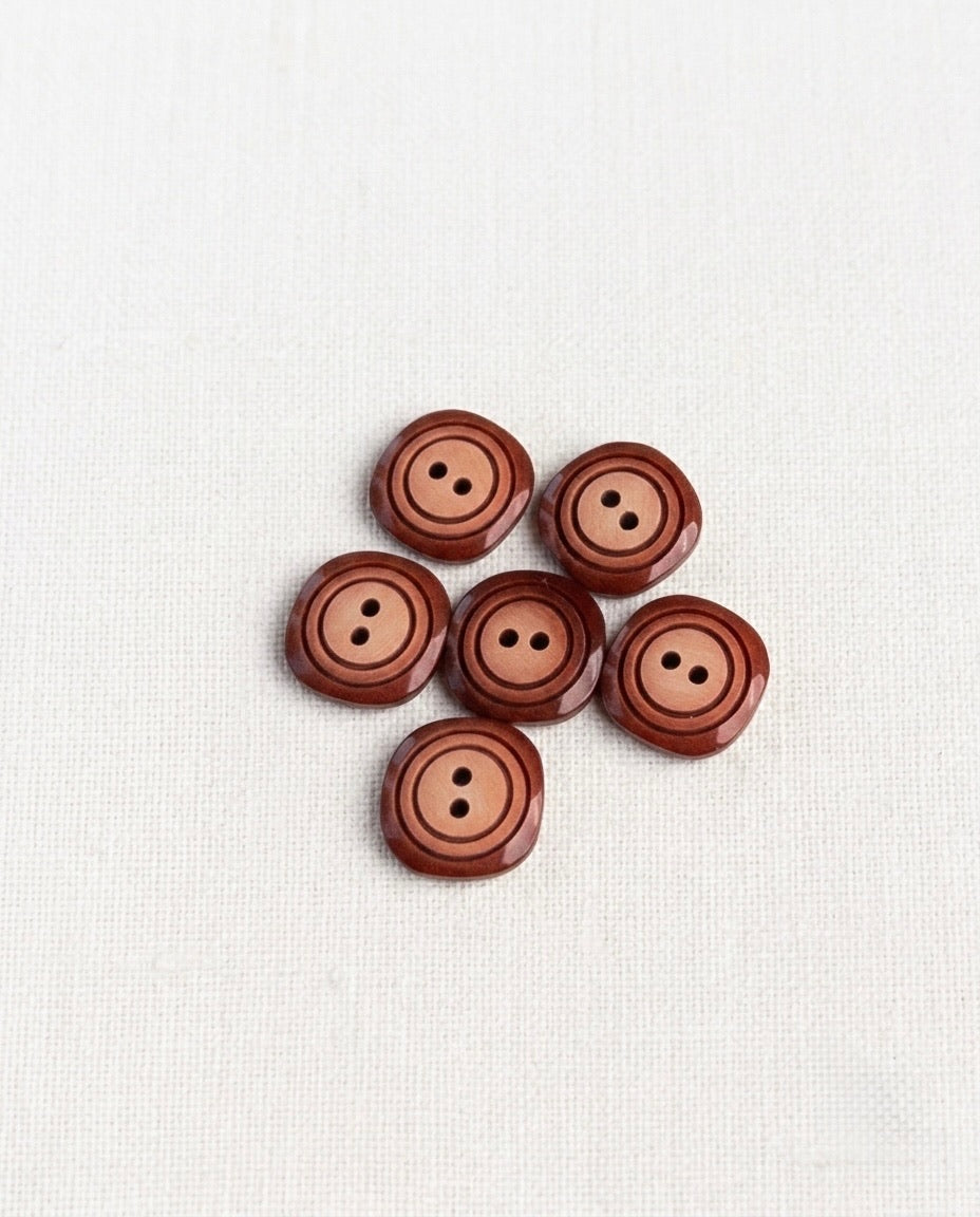 Boutons carrés dégradé bordeaux et pêche de 14 mm vus de dessus sur un tissu blanc