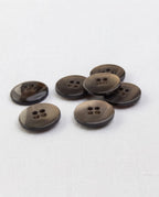 Boutons taupe de 18 mm à 4 trous vus de biais, bord plus foncé, dont un retourné