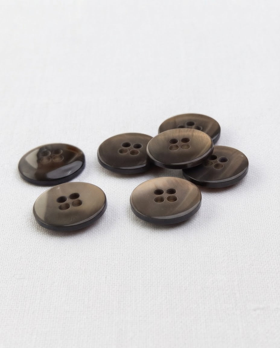 Boutons taupe de 18 mm à 4 trous vus de biais, bord plus foncé, dont un retourné