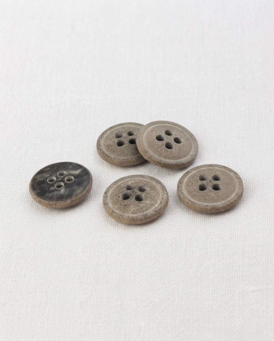Cinq boutons ronds effet pierre gris kaki de 15 mm à 4 trous, surface mouchetée et mate, dont un vu de dos