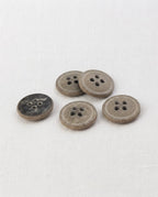 Cinq boutons ronds effet pierre gris kaki de 15 mm à 4 trous, surface mouchetée et mate, dont un vu de dos