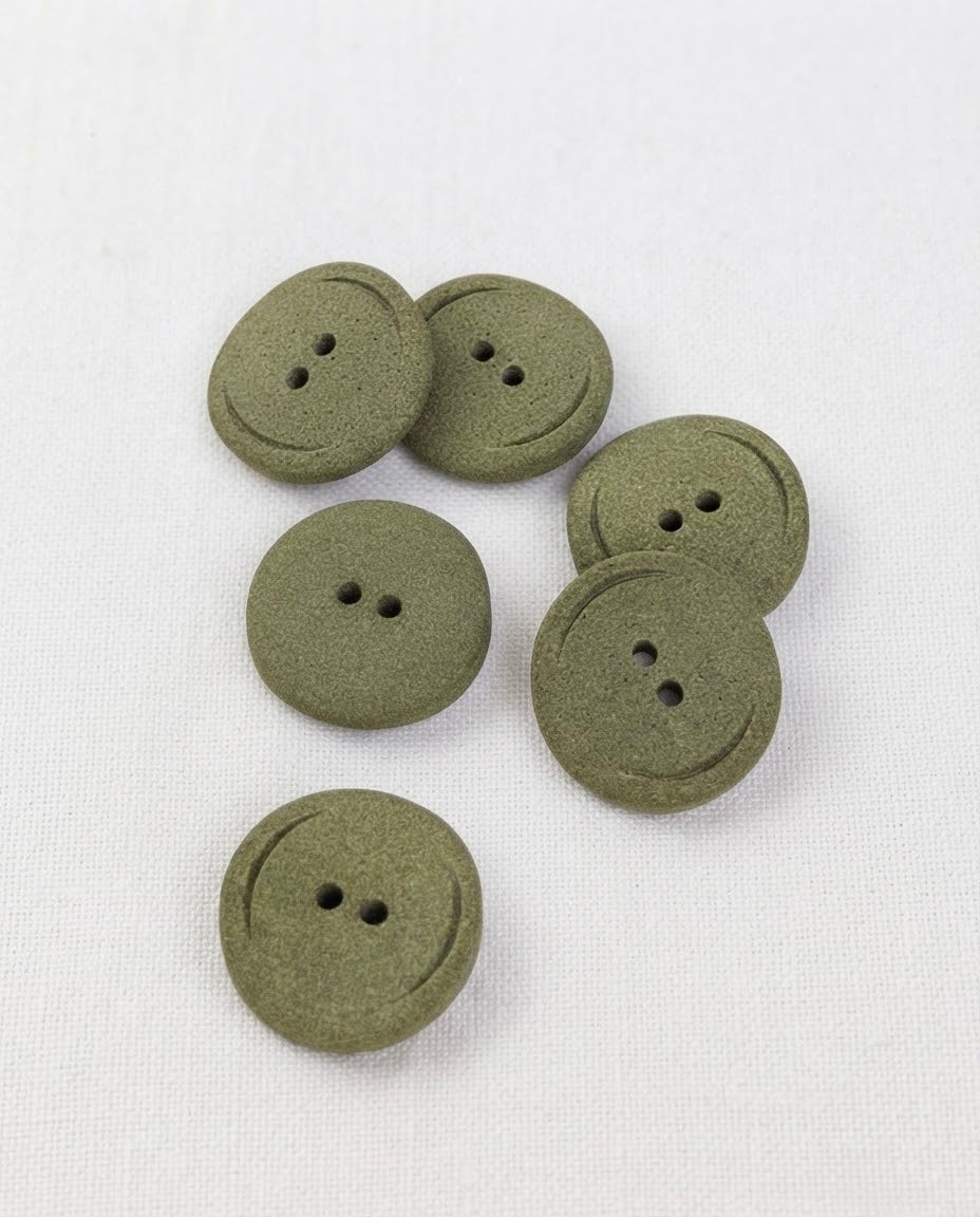 Boutons ronds vert kaki mat de 22 mm à 2 trous posés sur une toile écrue