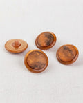 Quatre grands boutons ronds cuivre de 22 mm à queue, bord caramel et centre marbré brun et orange, dont un vu de dos
