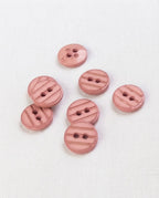 Sept boutons ronds rose ancien de 13 mm à 2 trous vus de dessus, un bouton retourné montre son dos