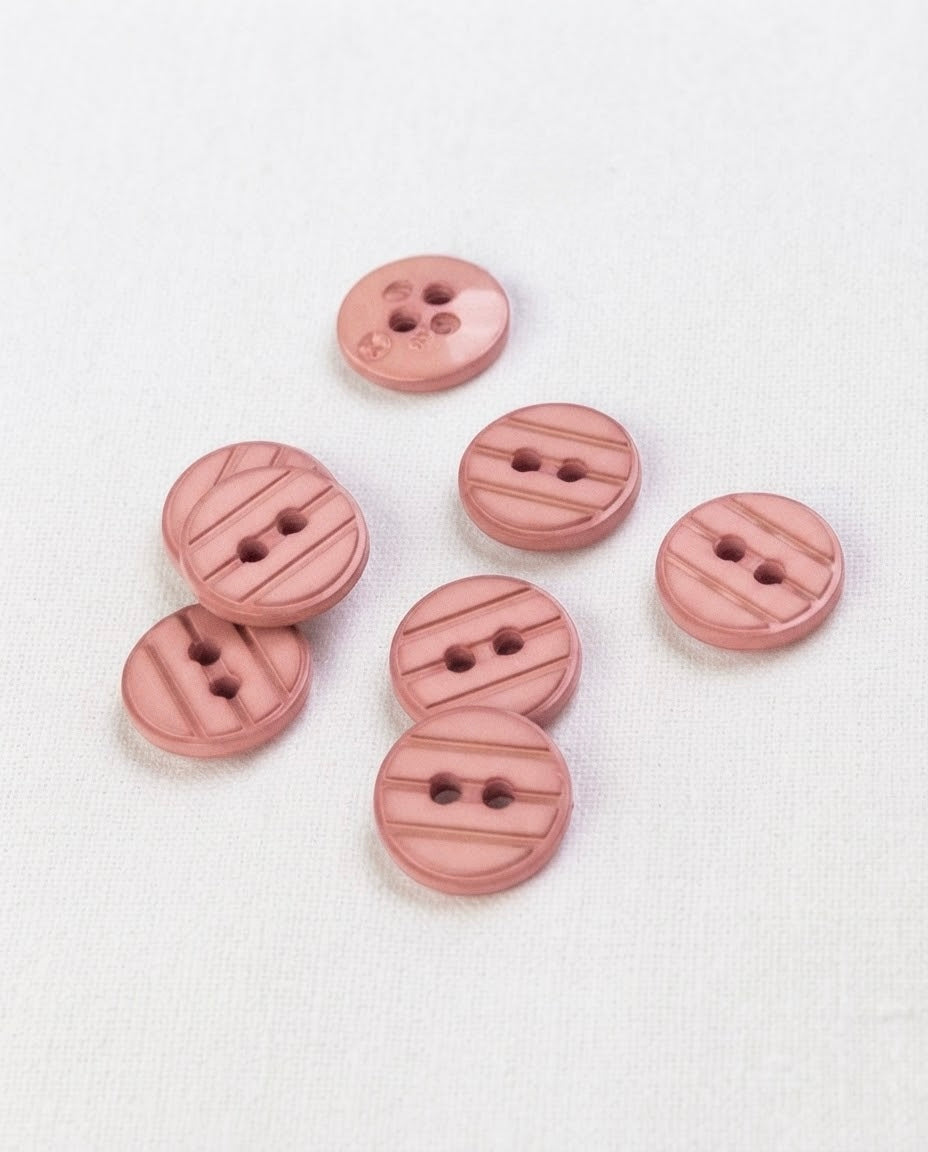 Sept boutons ronds rose ancien de 13 mm à 2 trous vus de dessus, un bouton retourné montre son dos