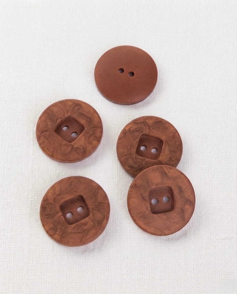 Quatre gros boutons ronds effet bois de bruyère de 22 mm groupés sur un tissu blanc