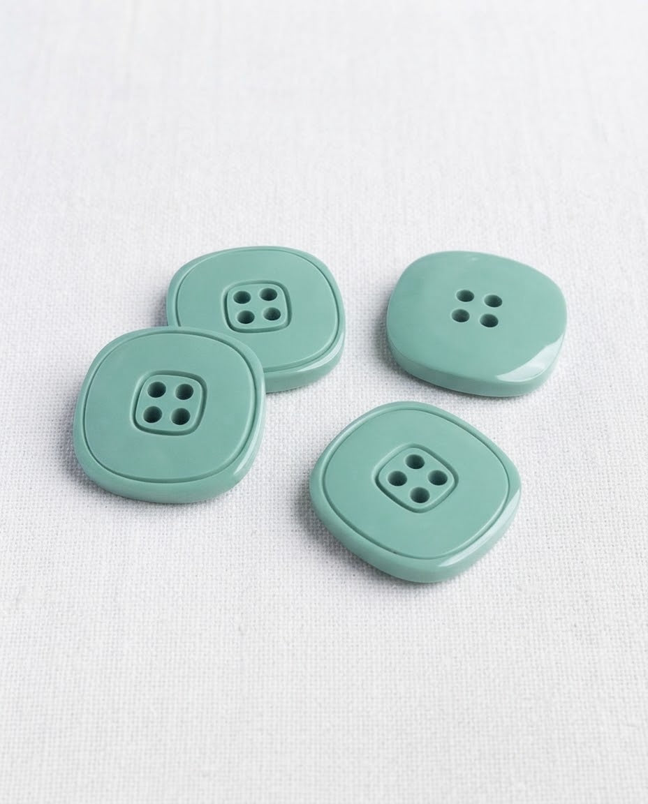 Quatre grands boutons carrés vert de gris de 20 mm à 4 trous, angles arrondis et cadre gravé au centre