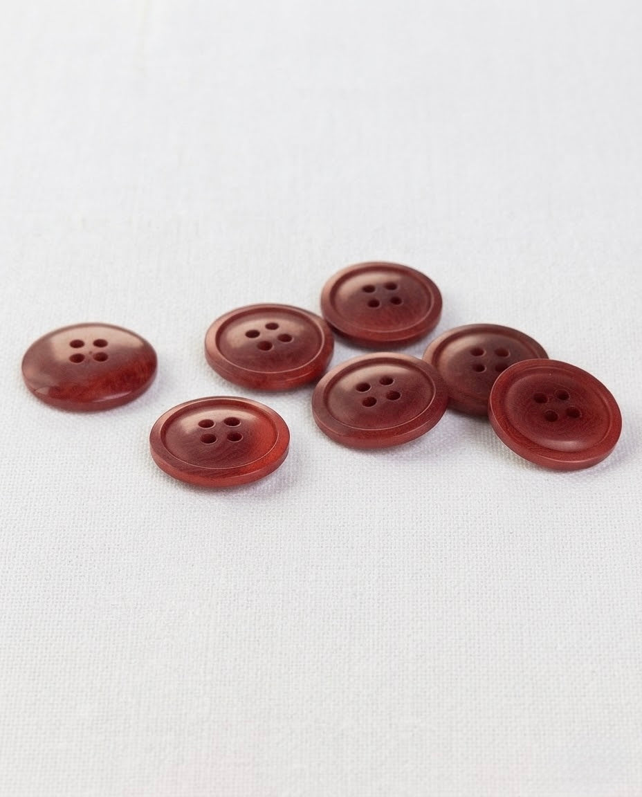 Sept boutons rouge effet bois de 17 mm à 4 trous vus de trois quarts, dont un vu de dos