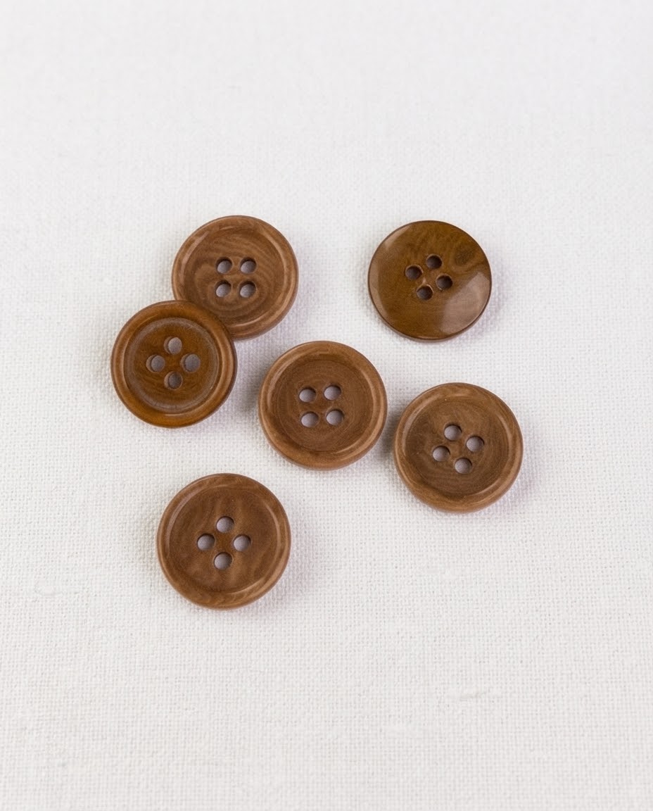 Boutons ronds effet bois de 15 mm à 4 trous vus de dessus sur un tissu blanc, veines brunes visibles, dont un retourné