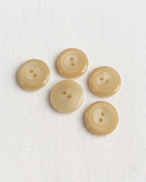 Cinq boutons ronds beige de 14 mm à 2 trous, avec un rebord en relief et un centre au reflet laiteux, dont un vu de dos
