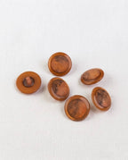 Boutons ronds cuivre de 17 mm vus de biais, un bouton retourné qui montre sa queue