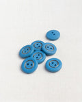 Sept boutons ronds bleu mat de 14 mm à 2 trous, cerclés d'un fin anneau doré, dont un vu de dos sans anneau