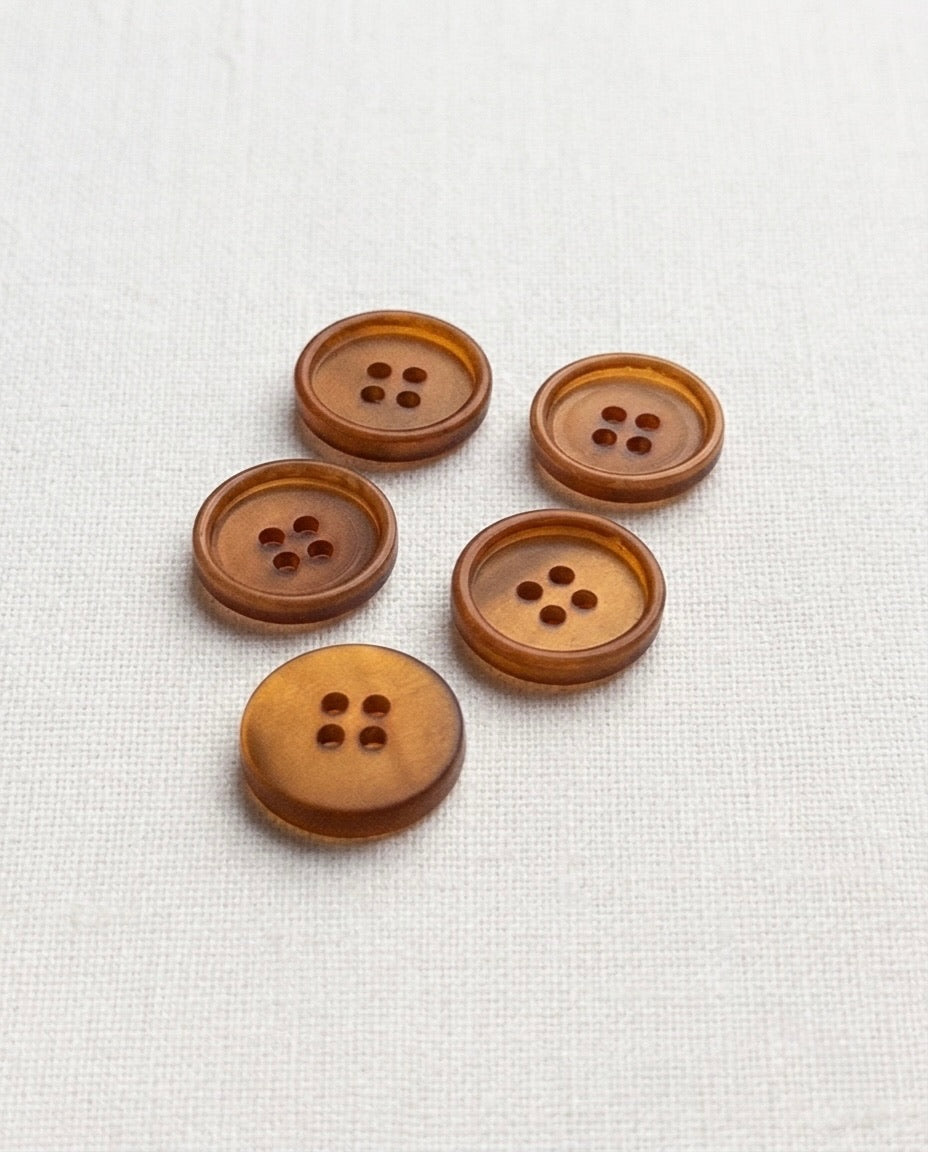 Boutons caramel ambré de 15 mm à 4 trous vus de biais, un bouton retourné montrant le dos lisse