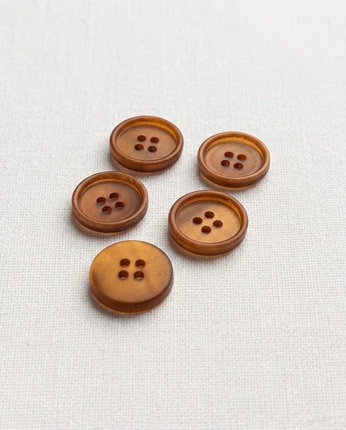 Boutons caramel ambré de 15 mm à 4 trous vus de biais, un bouton retourné montrant le dos lisse