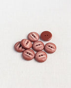 Huit boutons ronds brique rosé brillants de 12 mm à 2 trous, barrés d'une bande plus claire, dont un vu de dos