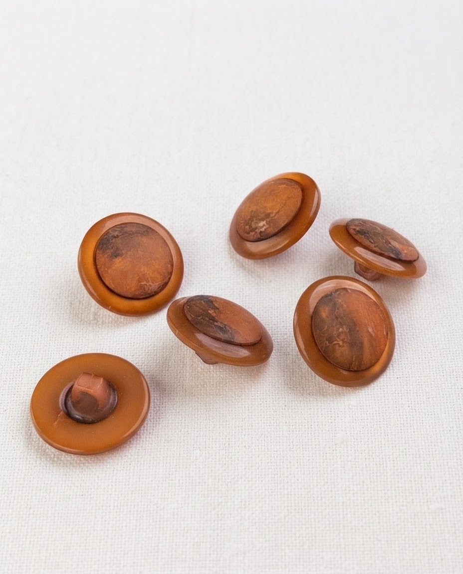 Six boutons ronds cuivre de 17 mm à queue, bord caramel brillant et centre marbré de brun, dont un vu de dos