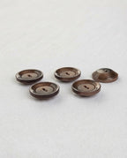 Boutons ronds marron de 22 mm à 2 trous vus de trois quarts, le bord foncé accroche la lumière
