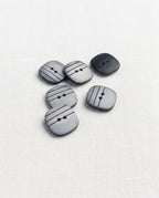 Six boutons carrés à angles arrondis gris perle nacré de 15 mm à 2 trous, rayures noires gravées, dont un vu de dos