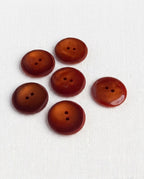 Six boutons rouille ambré de 21 mm à 2 trous vus de dessus, un bouton retourné montre son dos brillant