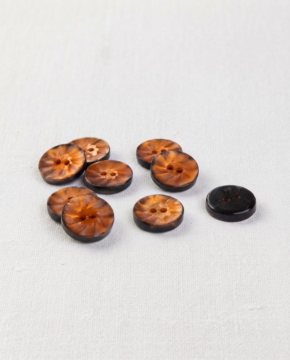 Huit petits boutons ronds ambre nacré de 12 mm à 2 trous, motif rayonnant au centre et bord plus foncé, dont un vu de dos brun