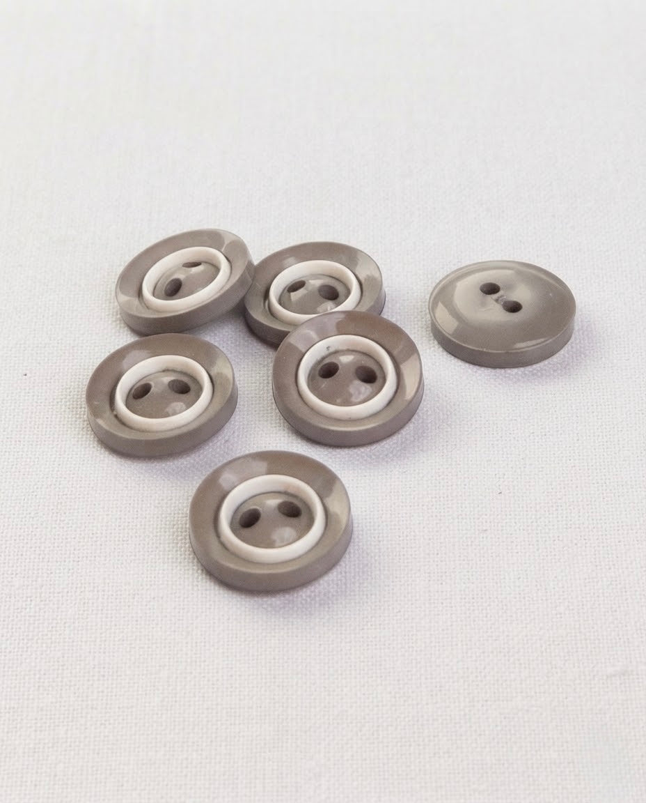 Six boutons ronds gris taupe brillants de 14 mm à 2 trous, cerclés d'un anneau blanc, vus de biais