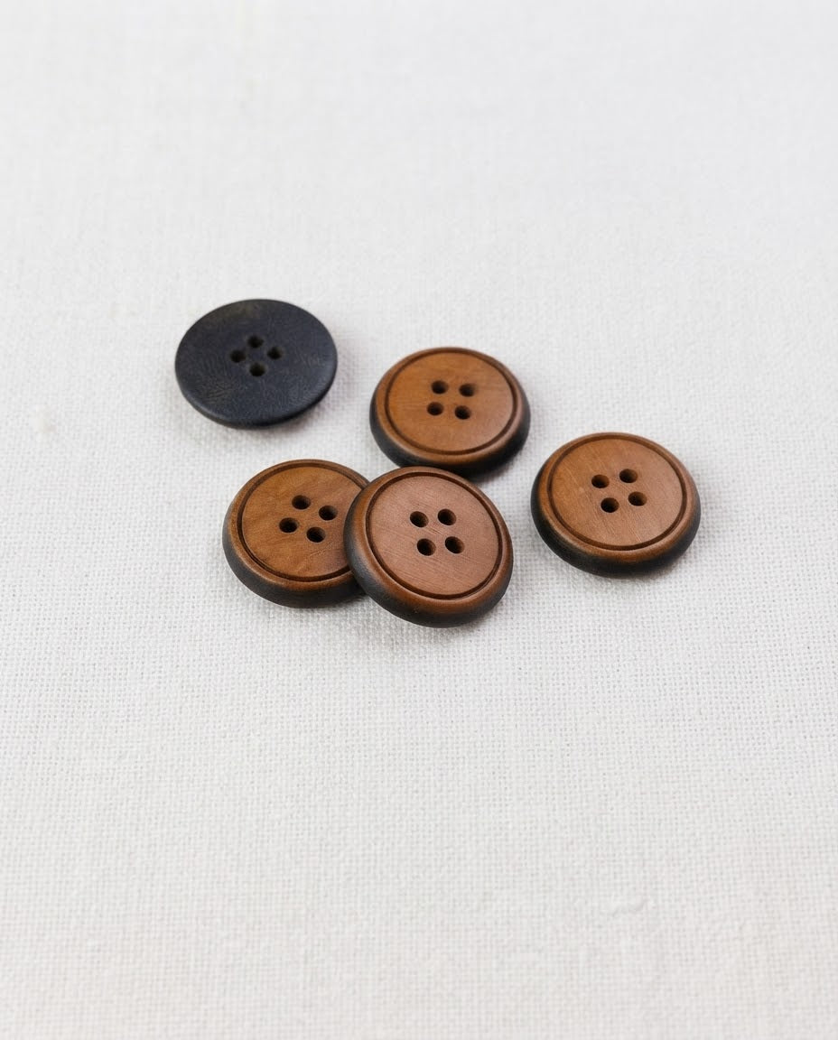Boutons ronds effet bois de 17 mm à 4 trous vus de biais, centre caramel et bord sombre, dont un retourné