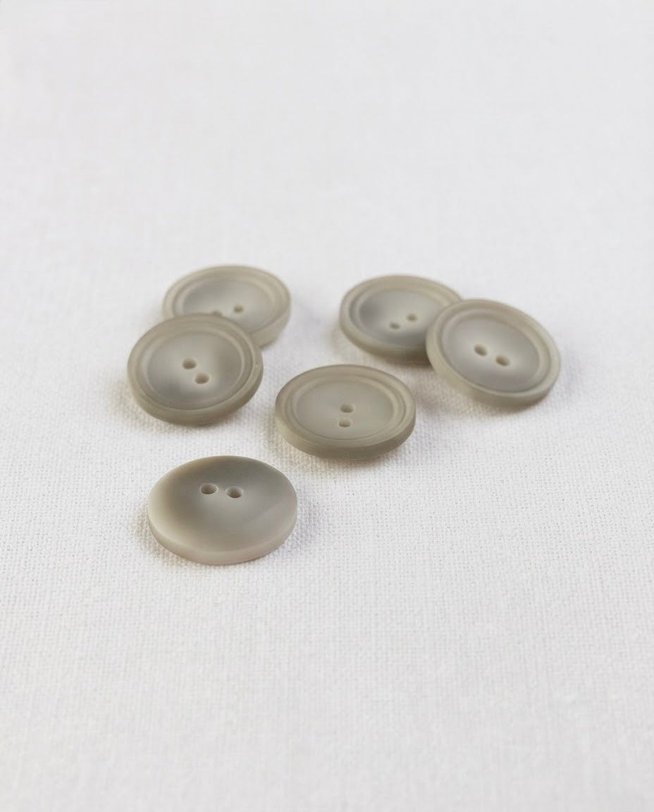 Six boutons ronds beige grisé mat de 17 mm à 2 trous, centre creusé cerné de deux cercles, dont un vu de dos