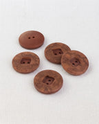 Gros boutons marbrés brun de 22 mm vus de biais, un bouton retourné montre son dos brun uni