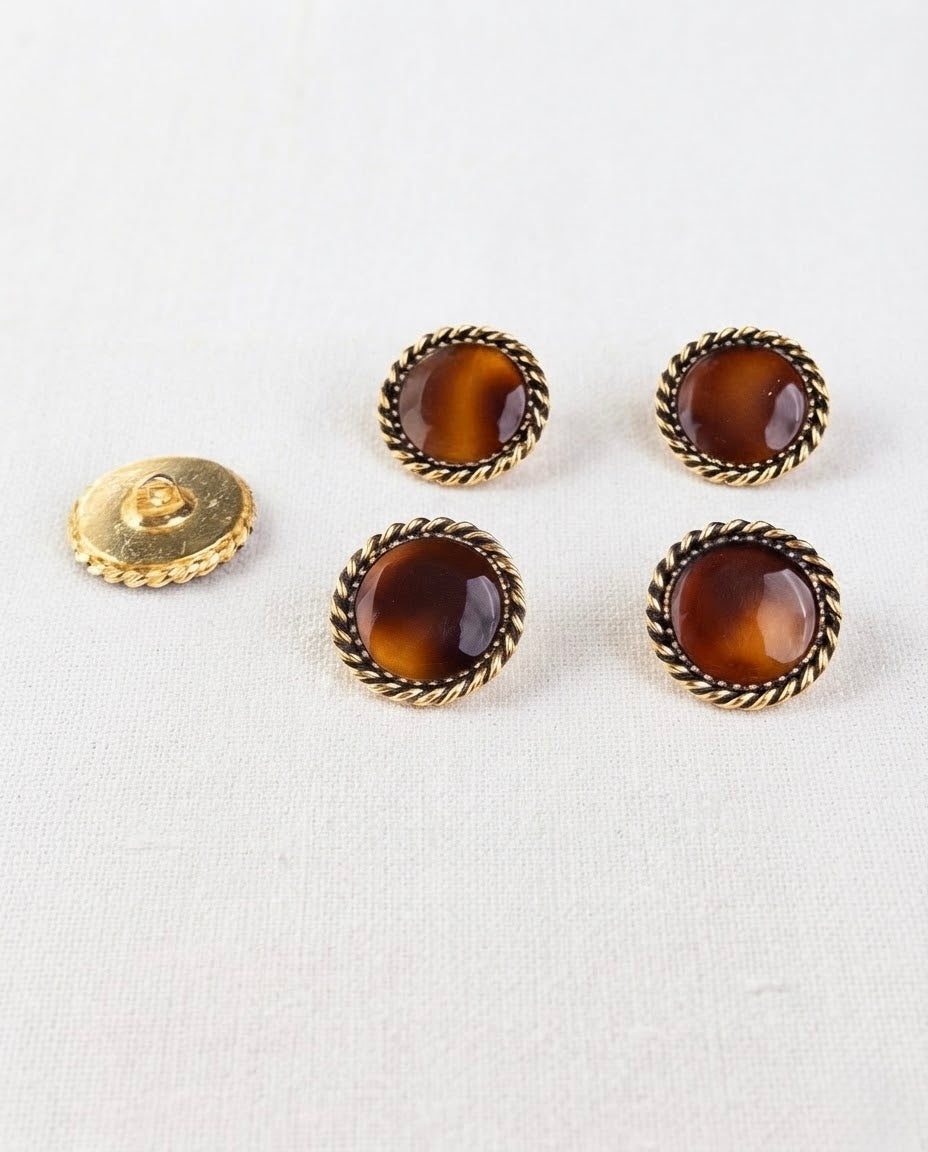 Quatre boutons caramel et doré de 19 mm vus de dessus, à côté d'un bouton retourné qui montre sa queue dorée