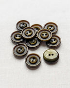 Douze boutons ronds vert olive foncé de 15 mm à 2 trous, anneaux gravés autour des trous, dont un vu de dos marbré