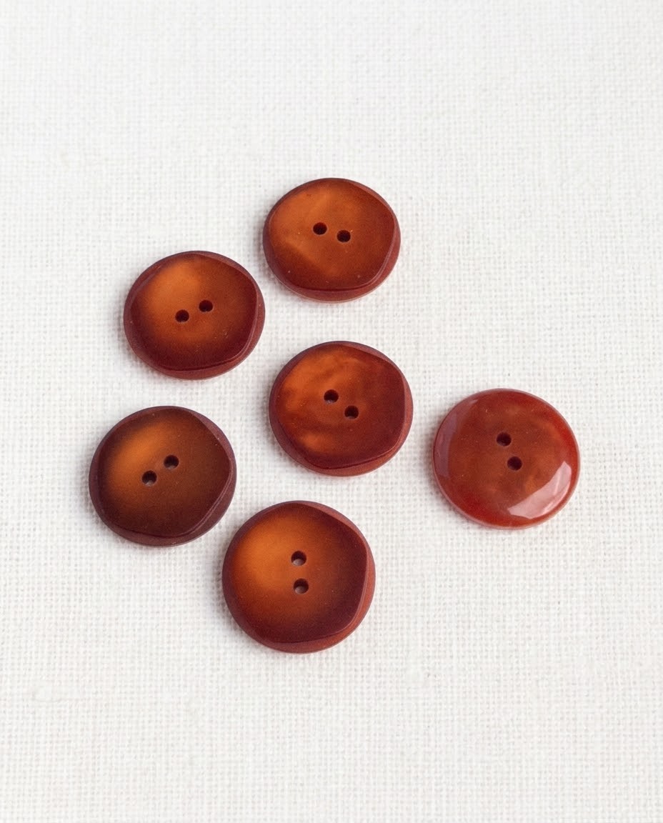Six grands boutons ronds rouille ambré de 21 mm à 2 trous, contour légèrement irrégulier, dont un vu de dos brillant