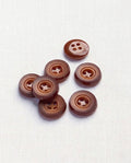 Sept boutons ronds rouille mat de 14 mm à 4 trous, creux en étoile autour des trous, dont un vu de dos brillant