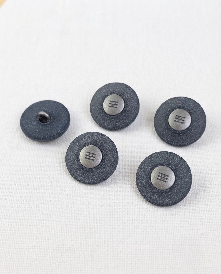 Cinq grands boutons ronds bleu jean de 22 mm à queue, large bord mat granuleux et petit centre argenté gravé, dont un vu de dos