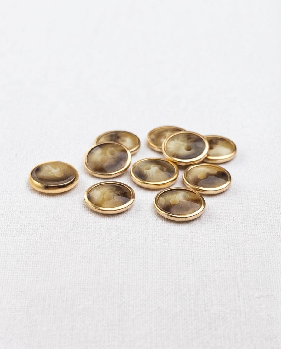 Boutons effet corne et doré de 12 mm à 2 trous vus de biais, le cercle doré forme un fin rebord