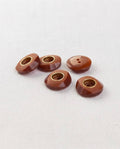 Cinq boutons ronds marron acajou de 18 mm à 2 trous, anneau doré encastré au centre et pourtour à facettes, dont un vu de dos