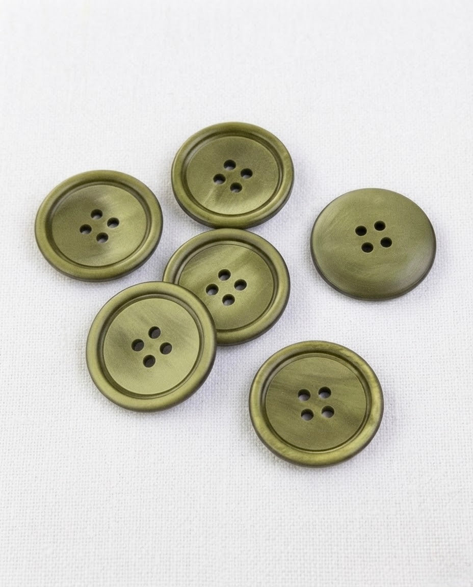 Boutons ronds vert olive clair de 22 mm à 4 trous posés sur une toile écrue
