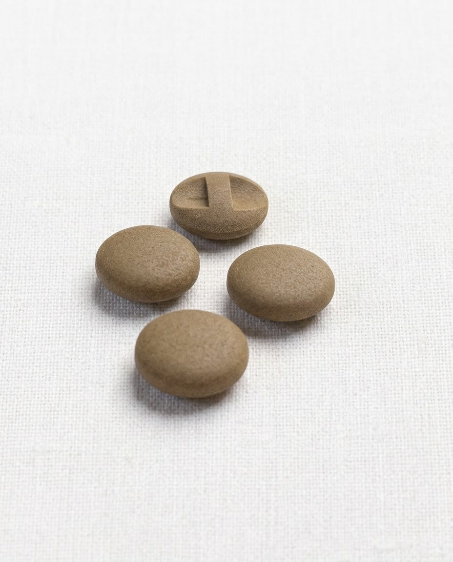 Boutons bombés brun liège de 17 mm à queue encastrée vus de biais sur une toile écrue