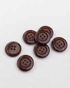 Sept boutons ronds marron chocolat de 17 mm à 4 trous, bord brillant et centre mat, dont un vu de dos