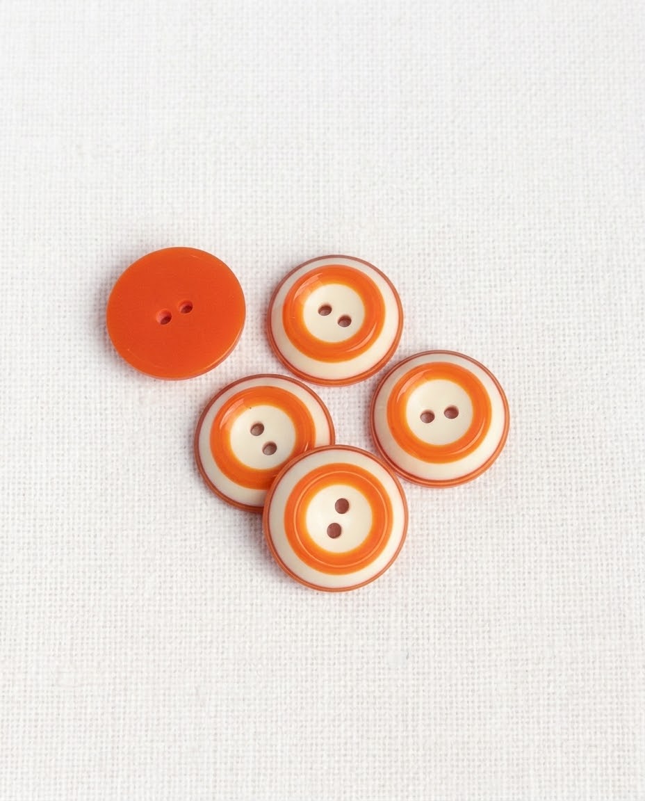 Cinq boutons ronds à cercles orange et crème de 18 mm à 2 trous vus de dessus