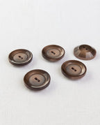 Cinq gros boutons marron de 22 mm à 2 trous, dont un retourné qui montre son dos bombé
