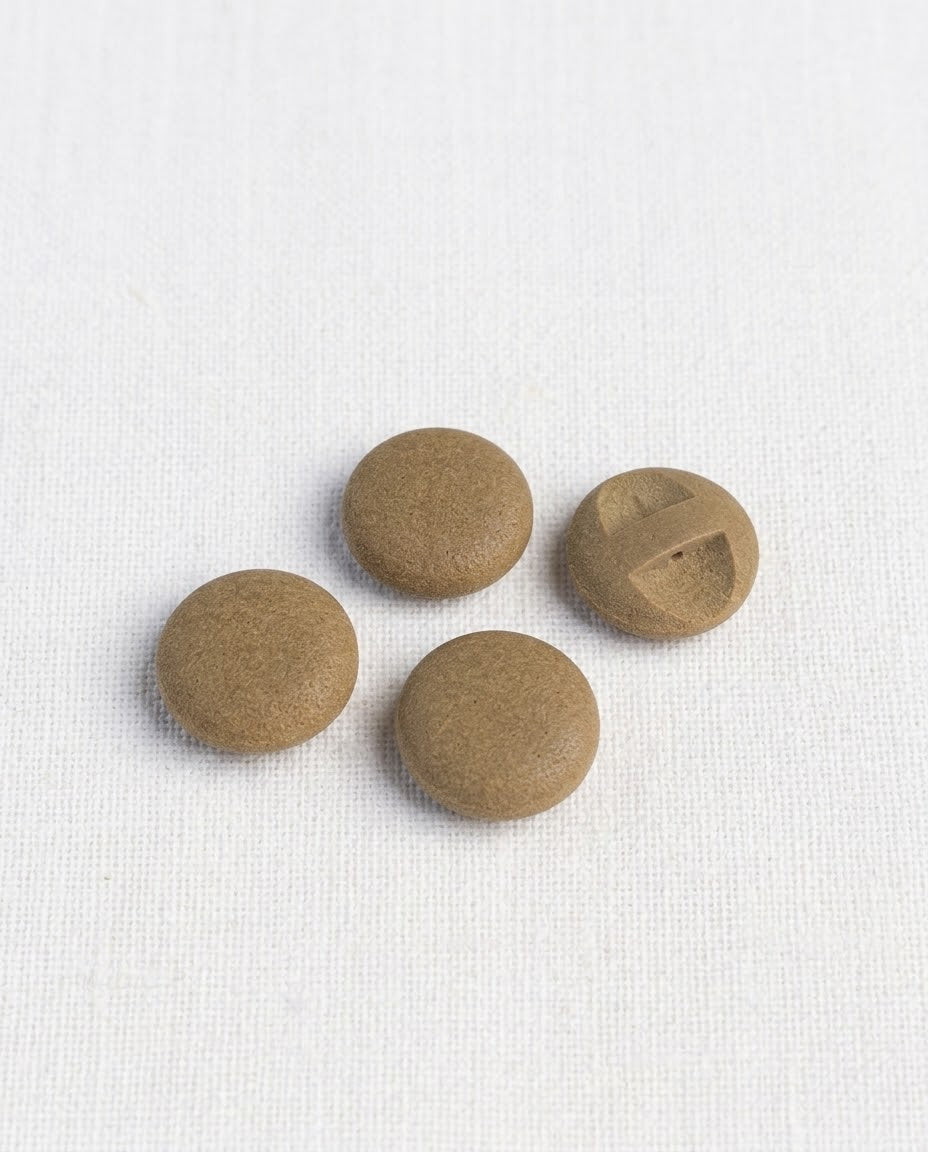 Quatre boutons ronds brun liège de 17 mm à queue encastrée, surface grainée et mate, dont un retourné montrant sa barrette