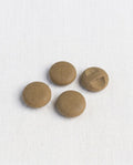 Quatre boutons ronds brun liège de 17 mm à queue encastrée, surface grainée et mate, dont un retourné montrant sa barrette