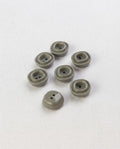 Sept petits boutons carrés gris vert brillants de 12 mm à 2 trous, avec un bourrelet carré en relief, dont un vu de dos
