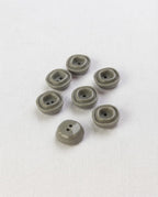 Sept petits boutons carrés gris vert brillants de 12 mm à 2 trous, avec un bourrelet carré en relief, dont un vu de dos