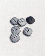 Boutons carrés gris rayés de noir de 15 mm à 2 trous posés sur une toile écrue, esprit marinière