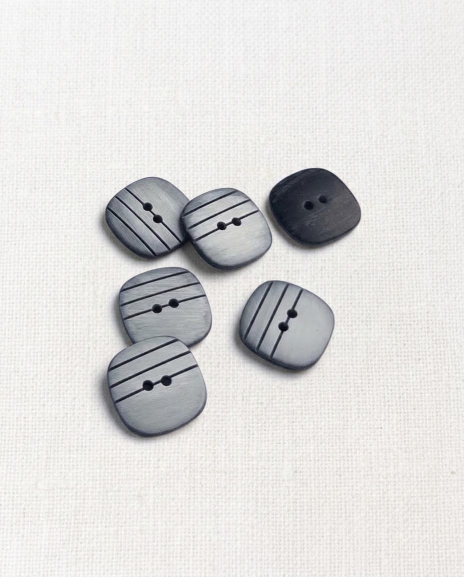 Boutons carrés gris rayés de noir de 15 mm à 2 trous posés sur une toile écrue, esprit marinière