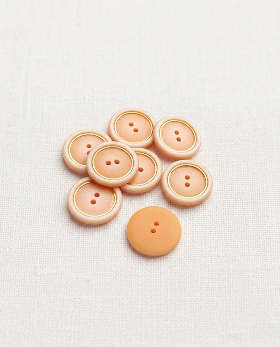 Sept boutons pêche et doré de 18 mm à 2 trous, un bouton retourné montre son dos pêche uni