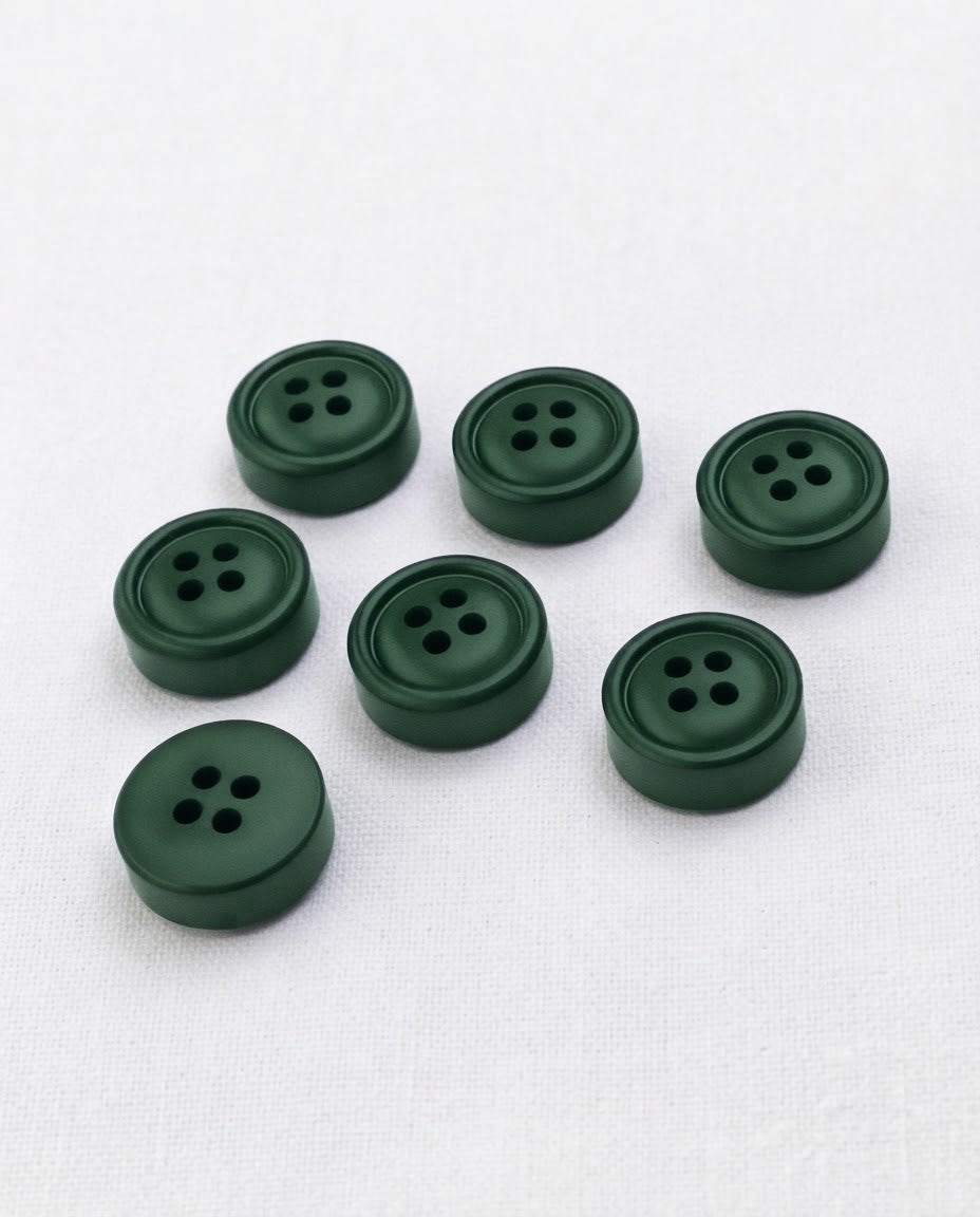 Sept boutons ronds épais vert sapin de 18 mm à 4 trous, centre creusé entouré d'un rebord, dont un vu de dos